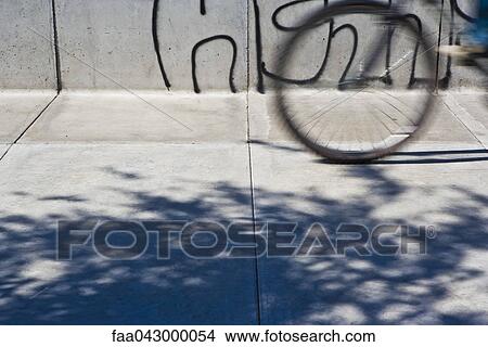 Bicycle in motion on sidewalk, cropped View Large Photo Image Picture - Bicycle in motion on sidewalk, cropped. Fotosearch