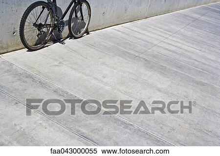 Stock Photography - Bicycle with chain hanging loose leaning against wall, cropped view. Fotosearch