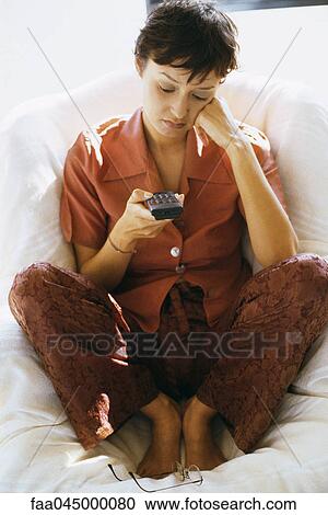 Stock Image - Bored woman holding remote control. Fotosearch