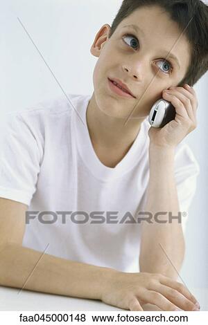Stock Photo - Boy using cell phone, glancing sideways. Fotosearch