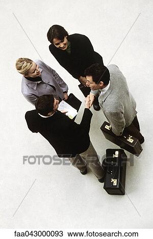 Stock Image - Business associates standing together, two men shaking hands, high angle view. Fotosearch