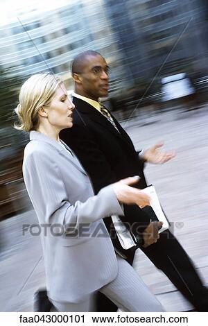 Businessman and businesswoman walking together in conversation View Large Photo Image Stock Image - Businessman and businesswoman walking together in conversation. Fotosearch
