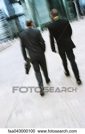Businessmen walking together along city sidewalk View Large Photo Image Stock Image - Businessmen walking together along city sidewalk. Fotosearch