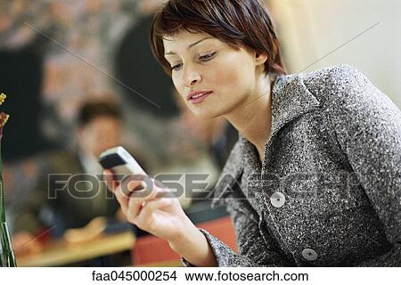Businesswoman looking at cell phone View Large Photo Image Picture - Businesswoman looking at cell phone. Fotosearch