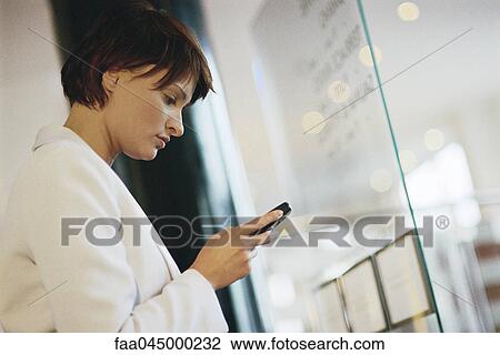 Businesswoman looking at cell phone, side view View Large Photo Image Stock Image - Businesswoman looking at cell phone, side view. Fotosearch