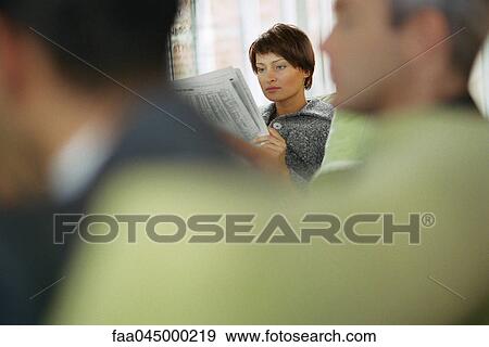 Stock Photo - Businesswoman reading newspaper in waiting room. Fotosearch