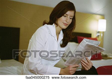 Stock Photography - Businesswoman reading newspaper in hotel room. Fotosearch