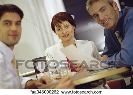 Colleagues working together at table, all smiling at camera View Large Photo Image Stock Image - Colleagues working together at table, all smiling at camera. Fotosearch
