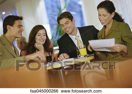 Colleagues working together at table with drinks View Large Photo Image Stock Photograph - Colleagues working together at table with drinks. Fotosearch