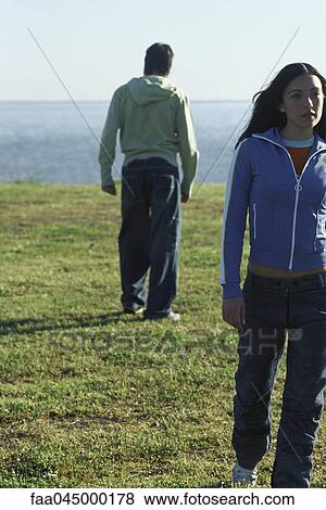 Couple walking apart from one another in field View Large Photo Image Stock Photo - Couple walking apart from one another in field. Fotosearch
