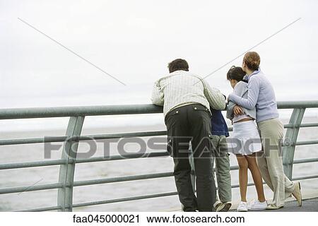 Family together at seawall railing looking at view View Large Photo Image Stock Image - Family together at seawall railing looking at view. Fotosearch