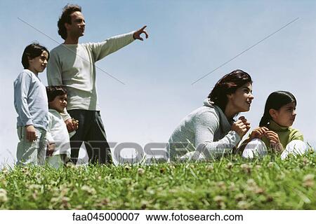 Stock Photo - Family together in grassy field enjoying view. Fotosearch