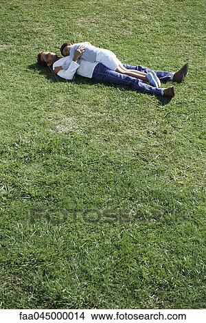 Picture - Father and daughter lying together in grassy field. Fotosearch