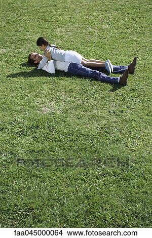 Father and daughter lying together in grassy field View Large Photo Image Picture - Father and daughter lying together in grassy field. Fotosearch