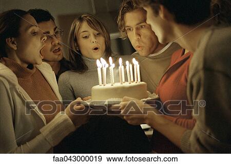 Stock Photo - Friends blowing out birthday candles together. Fotosearch