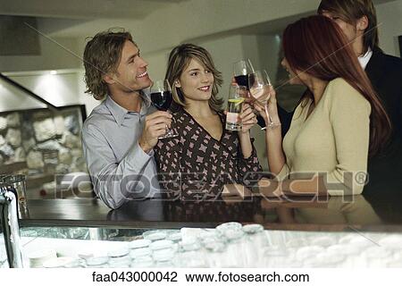 Stock Image - Friends clinking glasses, together at bar. Fotosearch
