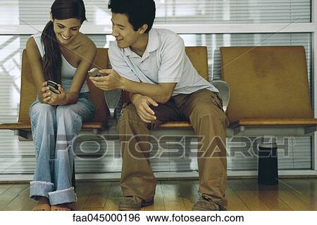 Stock Photograph - Friends comparing cell phones. Fotosearch