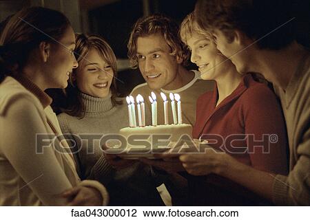 Friends gathered together around woman holding birthday cake View Large Photo Image Stock Image - Friends gathered together around woman holding birthday cake. Fotosearch