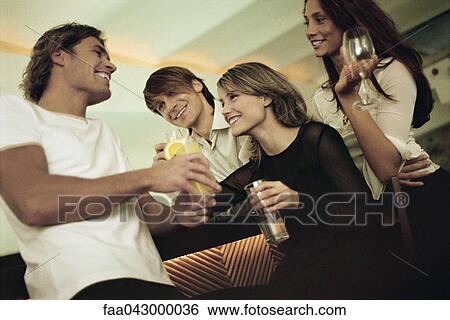 Stock Photograph - Friends having good time together at bar drinking mixed drinks. Fotosearch