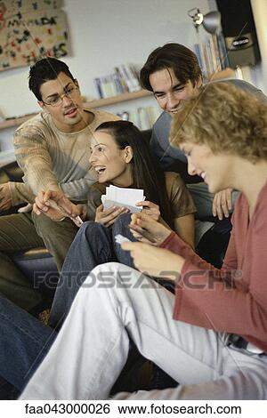 Stock Photograph - Friends sitting together sharing photos with one another. Fotosearch