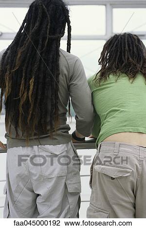 Stock Image - Friends with dreadlocks standing together, rear view. Fotosearch