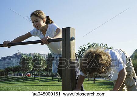 Girls playing on bars at park View Large Photo Image Stock Image - Girls playing on bars at park. Fotosearch