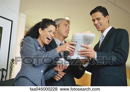 Group of executives looking at newspaper and laughing View Large Photo Image Stock Photo - Group of executives looking at newspaper and laughing. Fotosearch