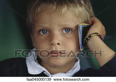 Little boy holding card against head, sulking View Large Photo Image Stock Photo - Little boy holding card against head, sulking. Fotosearch