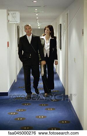 Male and female executives walking in hotel corridor View Large Photo Image Stock Photograph - Male and female executives walking in hotel corridor. Fotosearch