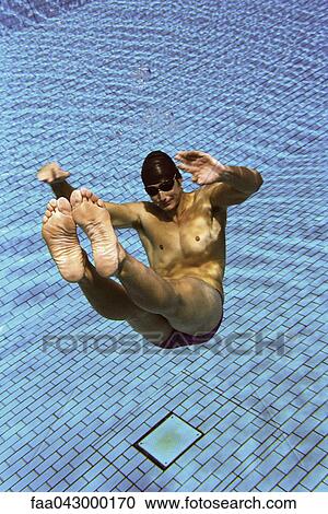 Stock Image - Male swimmer floating underwater in swimming pool. Fotosearch
