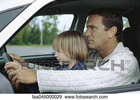 Man driving car with young son sitting on lap, both holding steering wheel View Large Photo Image Stock Photo - Man driving car with young son sitting on lap, both holding steering wheel. Fotosearch