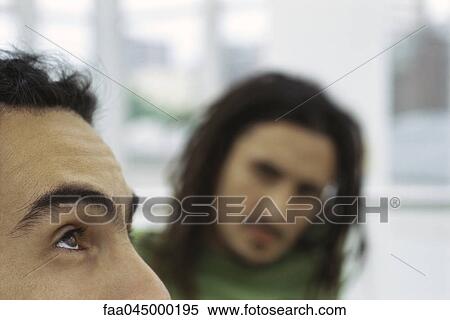 Stock Photography - Man looking up, friend watching in background, cropped. Fotosearch