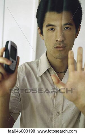 Man pressing hand against window, holding cell phone, looking at camera View Large Photo Image Stock Photo - Man pressing hand against window, holding cell phone, looking at camera. Fotosearch