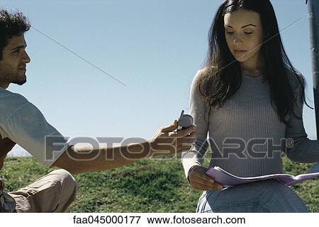 Man showing cell phone to woman looking at magazine View Large Photo Image Stock Photo - Man showing cell phone to woman looking at magazine. Fotosearch