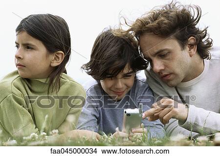 Man showing son cell phone, bored daughter looking away View Large Photo Image Picture - Man showing son cell phone, bored daughter looking away. Fotosearch