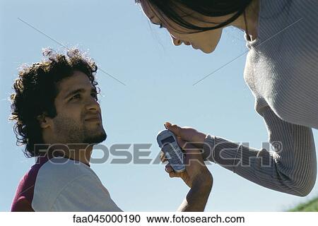 Stock Image - Man showing woman cell phone. Fotosearch