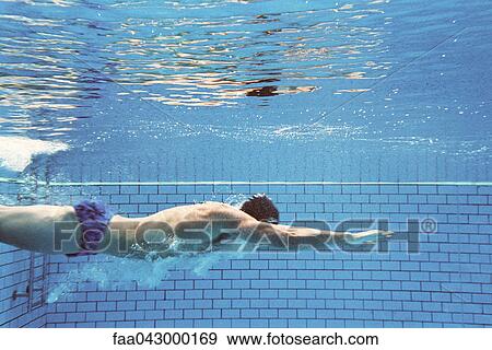 Stock Photo - Man swimming underwater, side view. Fotosearch