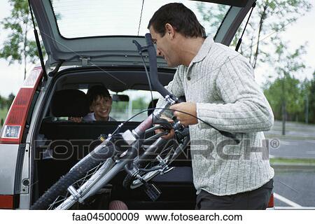 Man taking daughter's bicycle out of back of car View Large Photo Image Stock Photo - Man taking daughter's bicycle out of back of car. Fotosearch
