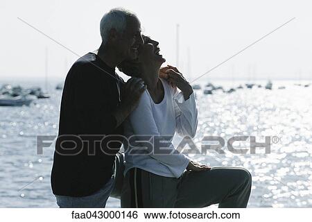 Mature couple laughing together, sea in background View Large Photo Image Stock Photograph - Mature couple laughing together, sea in background. Fotosearch