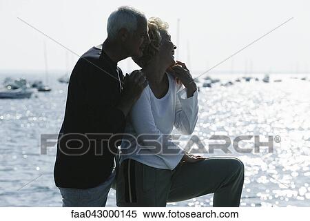 Mature couple standing together on pier, looking at view, backlit View Large Photo Image Stock Photography - Mature couple standing together on pier, looking at view, backlit. Fotosearch