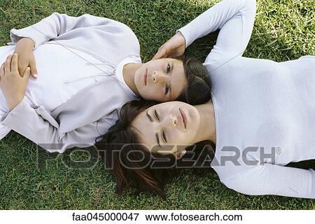 Stock Photo - Mother and daughter reclining together in grass, viewed from directly above. Fotosearch