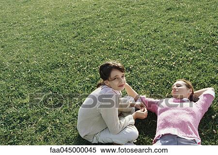 Mother and daughter relaxing on grass together, girl looking at camera View Large Photo Image Stock Photography - Mother and daughter relaxing on grass together, girl looking at camera. Fotosearch