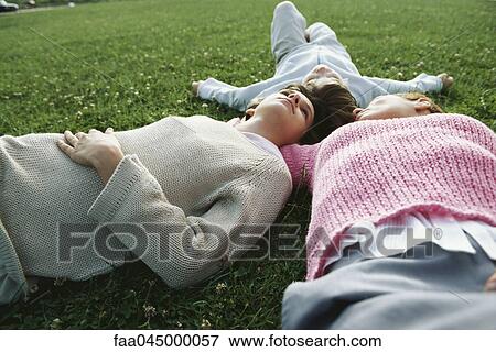 Stock Photo - Mother and two children lying together on grass. Fotosearch