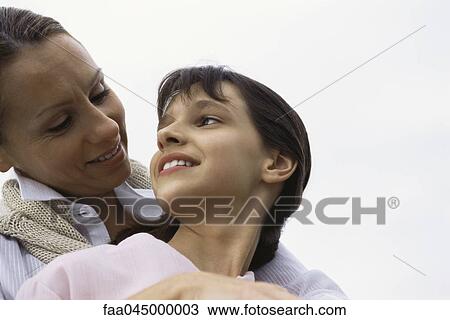 Stock Image - Mother embracing daughter, both smiling. Fotosearch