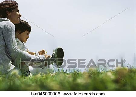 Stock Photograph - Mother sitting outdoors with son on lap, smiling. Fotosearch