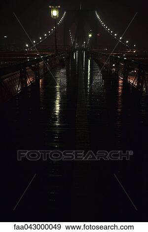 Pedestrian walkway across Brooklyn Bridge wet with rain at night, New York City, USA View Large Photo Image Stock Photo - Pedestrian walkway across Brooklyn Bridge wet with rain at night, New York City, USA. Fotosearch