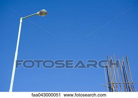 Stock Image - Rebar, street lamp against blue sky, low angle view. Fotosearch