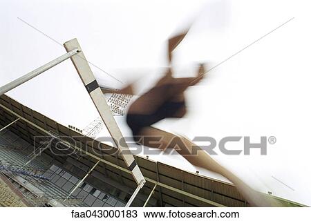 Stock Image - Runner jumping over hurdle, blurred. Fotosearch