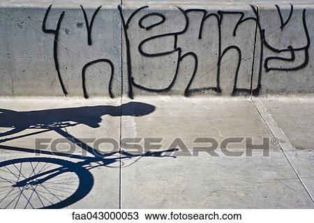 Shadow on sidewalk of person with bicycle, graffiti on wall View Large Photo Image Stock Image - Shadow on sidewalk of person with bicycle, graffiti on wall. Fotosearch