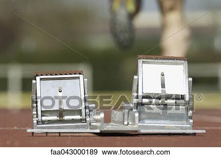 Stock Photo - Starting blocks, runner in background. Fotosearch